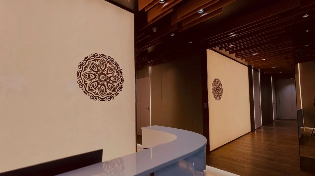 Recepção da Mais Beauté, com a mandala na parede, balcão branco e teto ripado de madeira